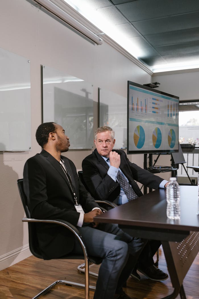 Two men in business attire engage in a professional discussion in a modern office.